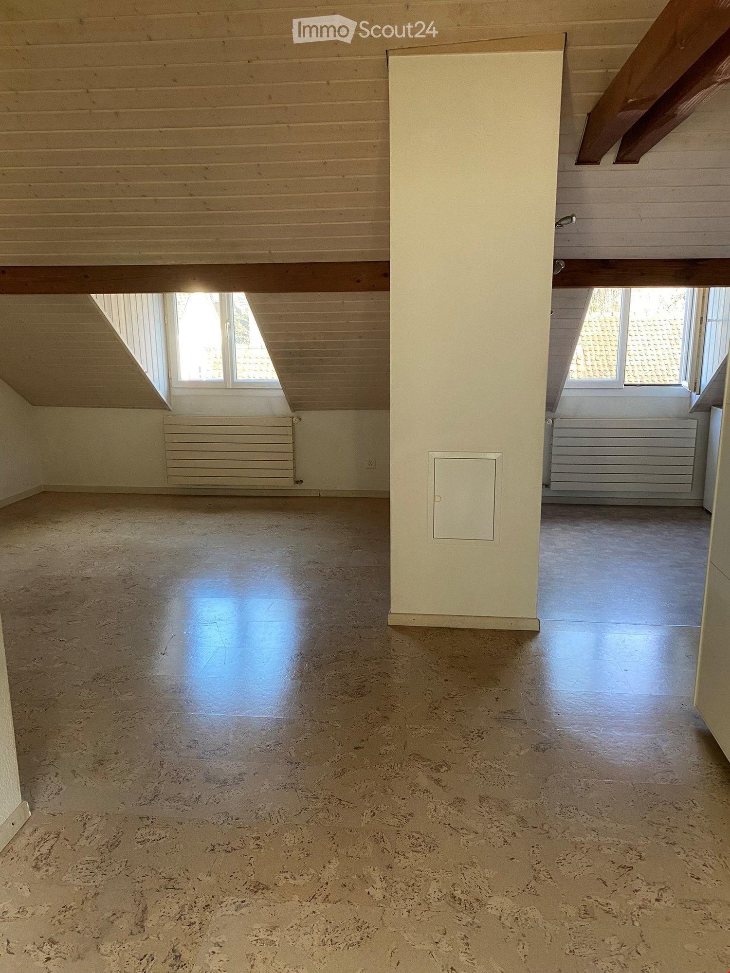 Empty attic room, radiators, windows, white pillar, wooden beams, beige tile