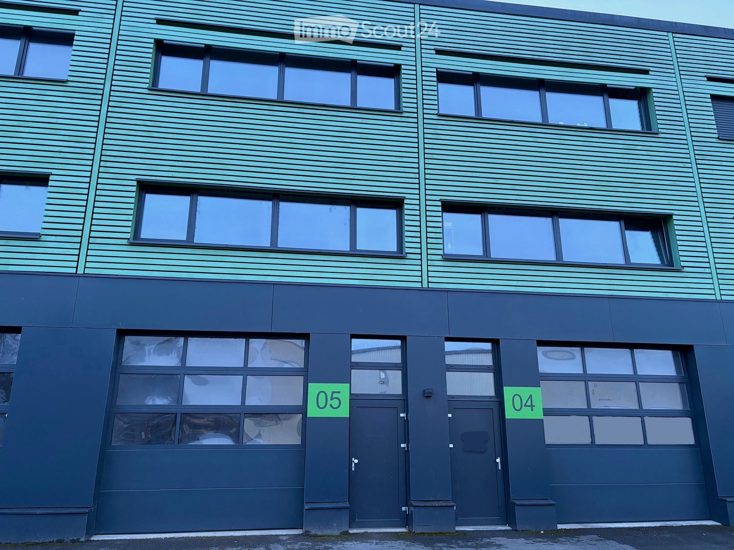 Blue facade, three glass windows per floor, two garage doors, labeled 04 and 05