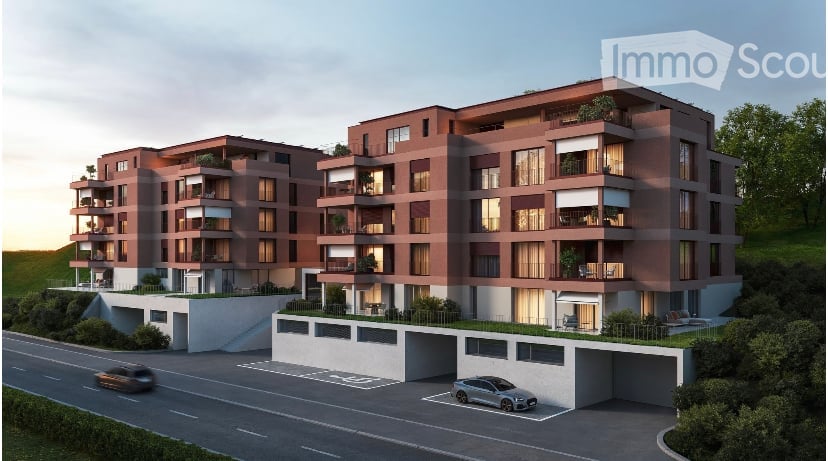 Multi-story apartment building with red brick exterior, balconies, and parking spaces in the front.