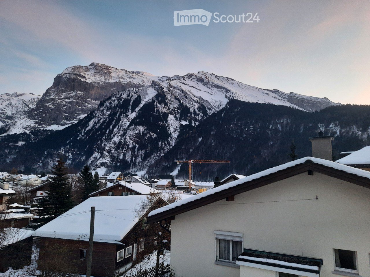 snowy mountains, houses, construction site, crane, snow-covered roofs
