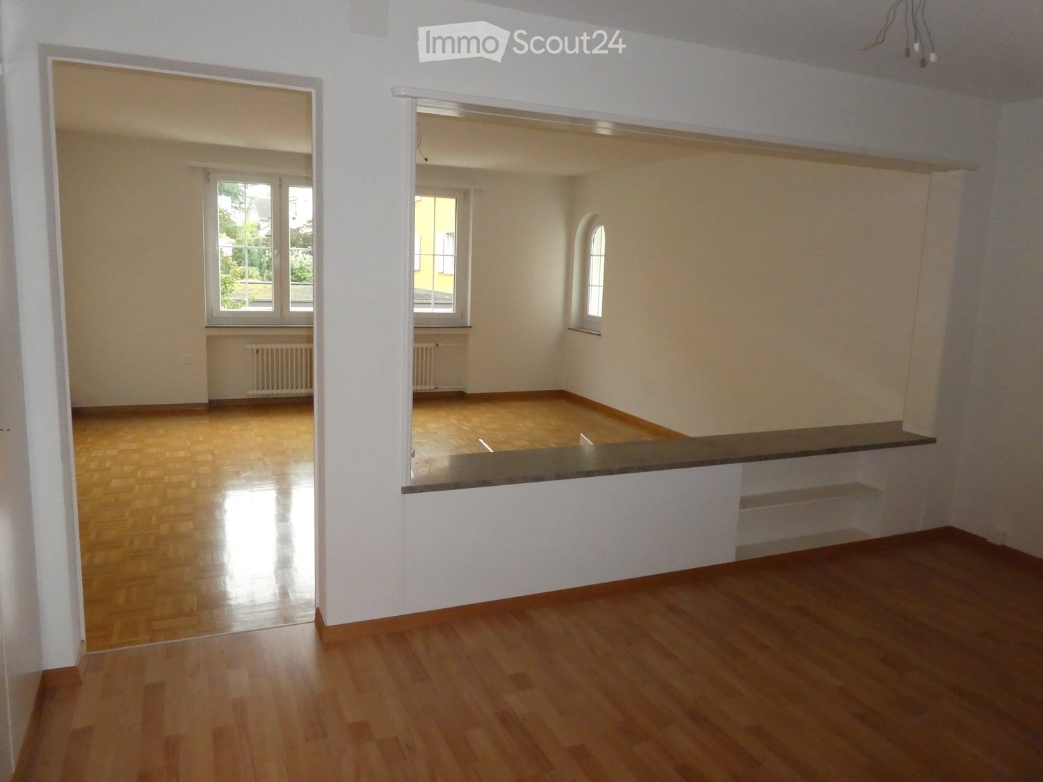 spacious room with wooden floor, white walls, glass windows, shelves and radiators