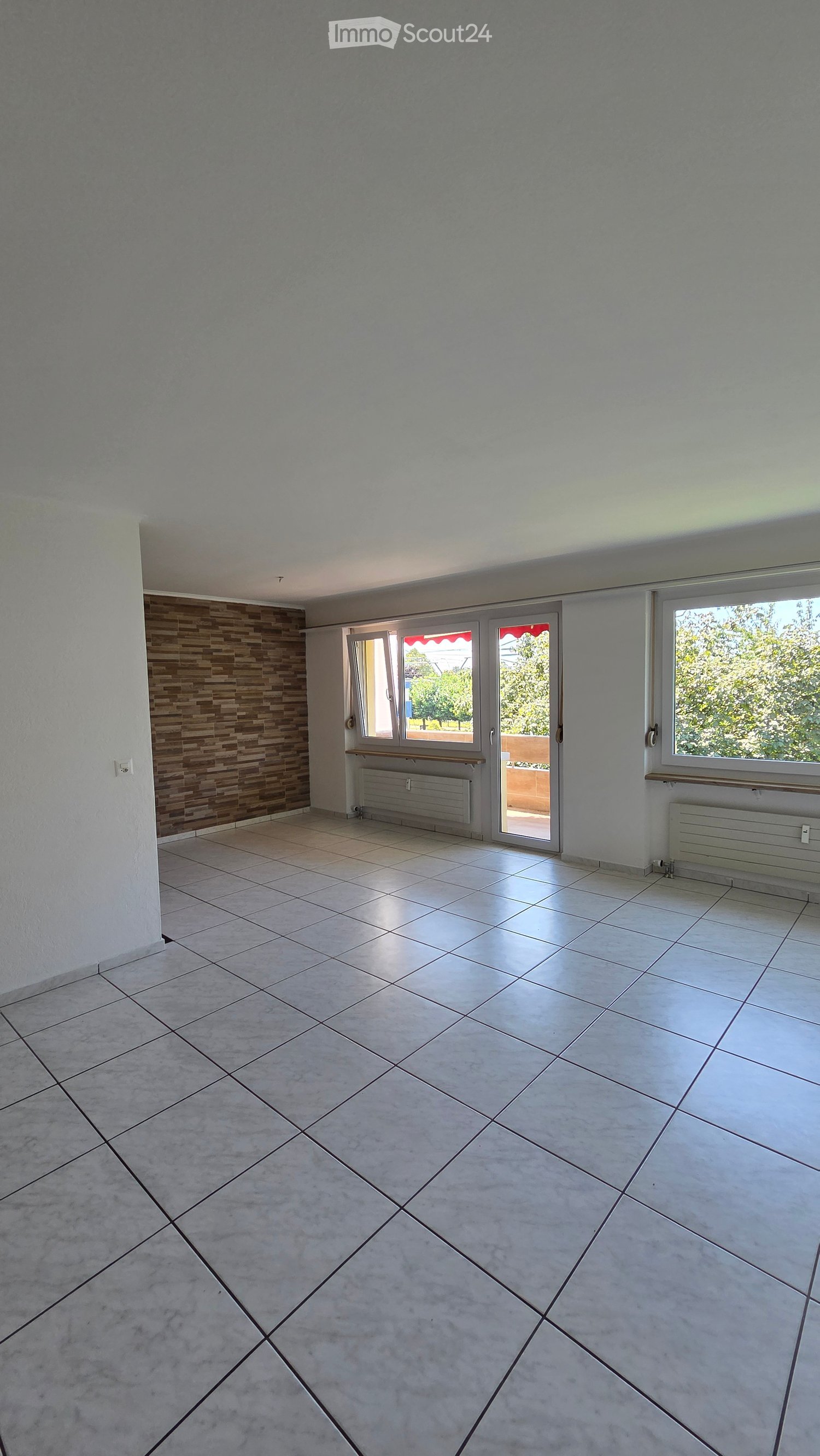 large room, tile flooring, two windows, sliding door, wooden wall paneling, heaters