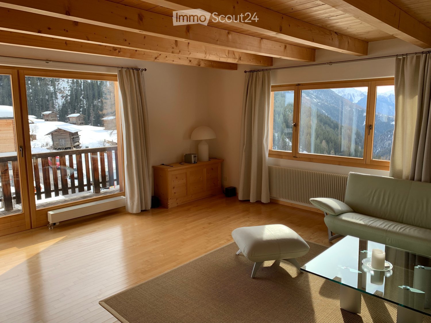 Wooden floor, large sliding glass doors, balcony, windows, sofa, ottoman, coffee table, white curtains, wooden cabinet, radiator