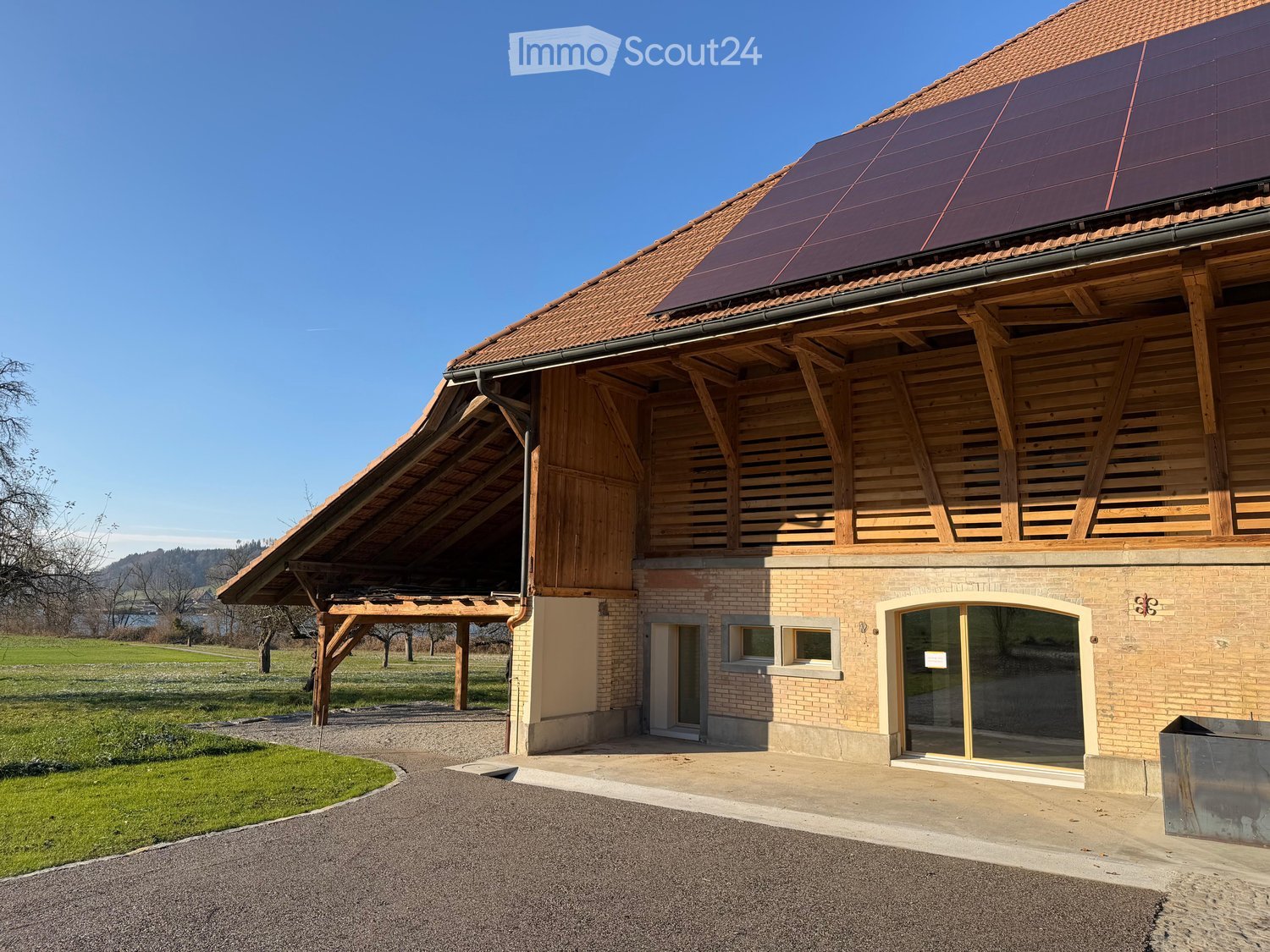 Detached house with wooden structure, solar panels on the roof, brick walls, paved driveway