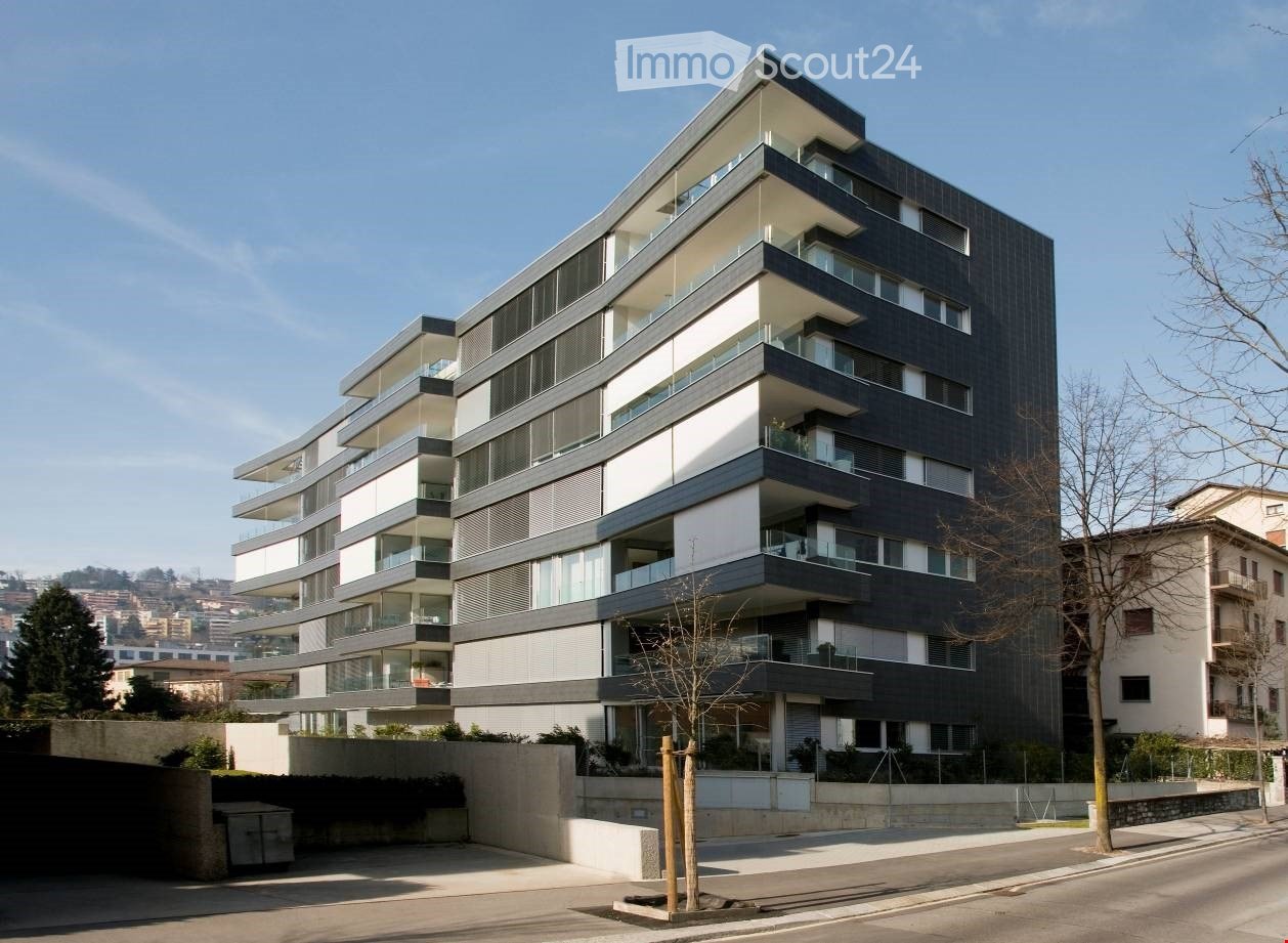 multi-story residential building with balconies, modern design, black and white facade, large windows, concrete retaining wall at base