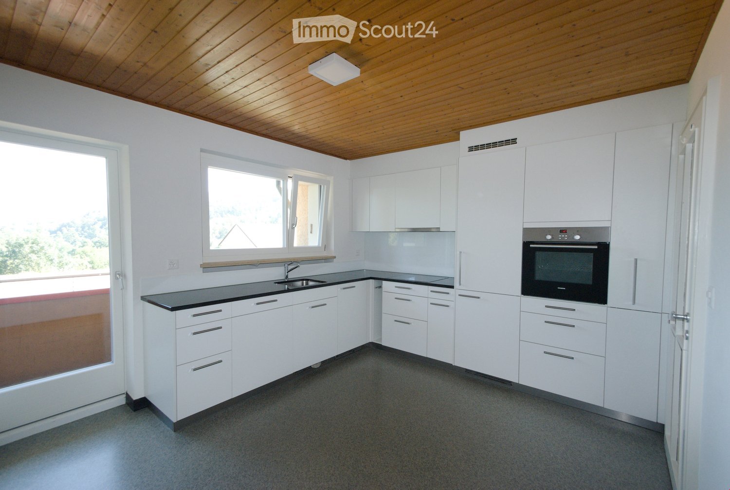 modern kitchen, white cabinets, black countertop, stainless steel appliances, sliding glass door, wooden ceiling