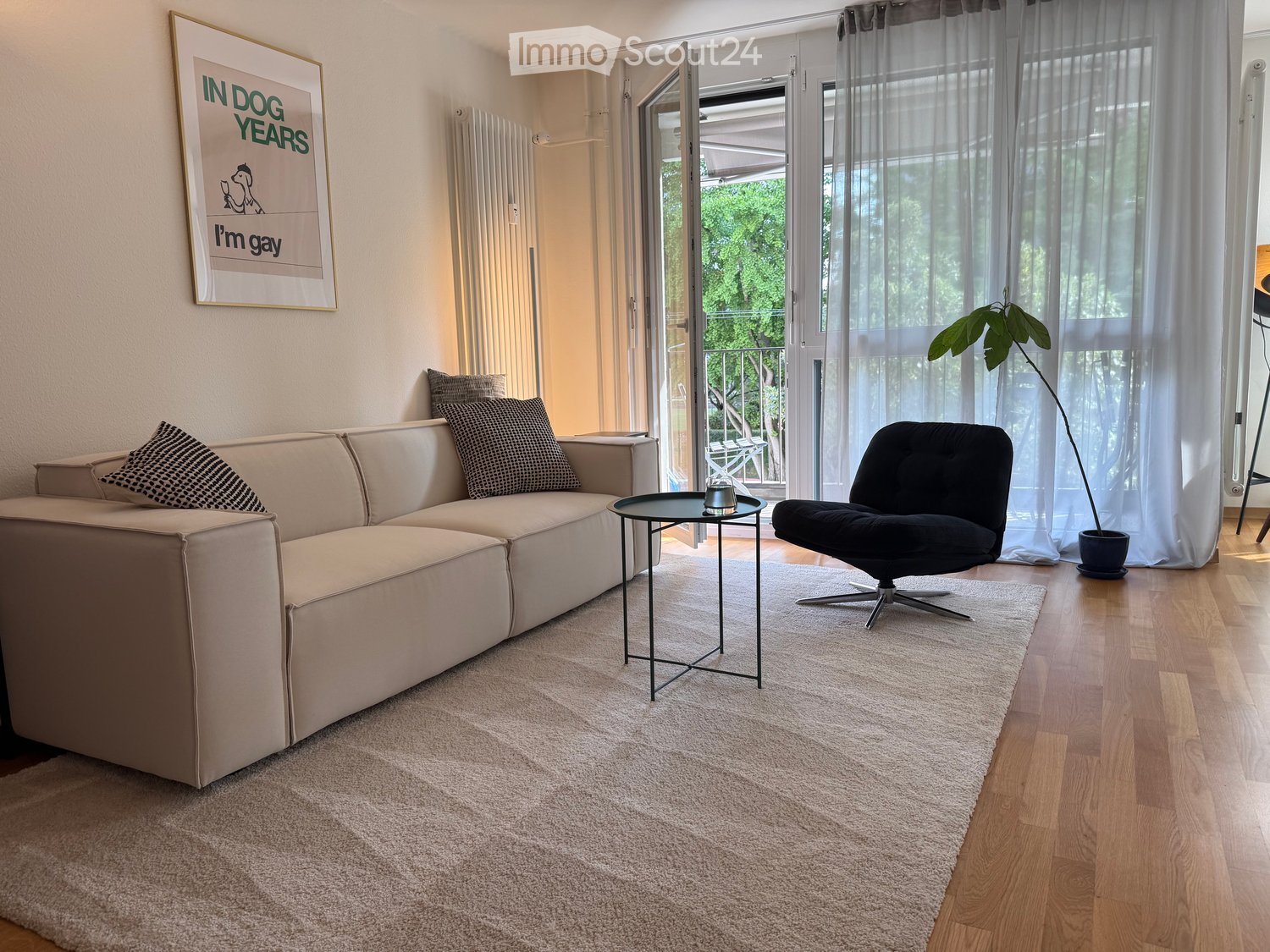 white walls, beige couch, cream rug, beige walls, potted plant, light wooden floor, window with balcony, black swivel chair, coffee table