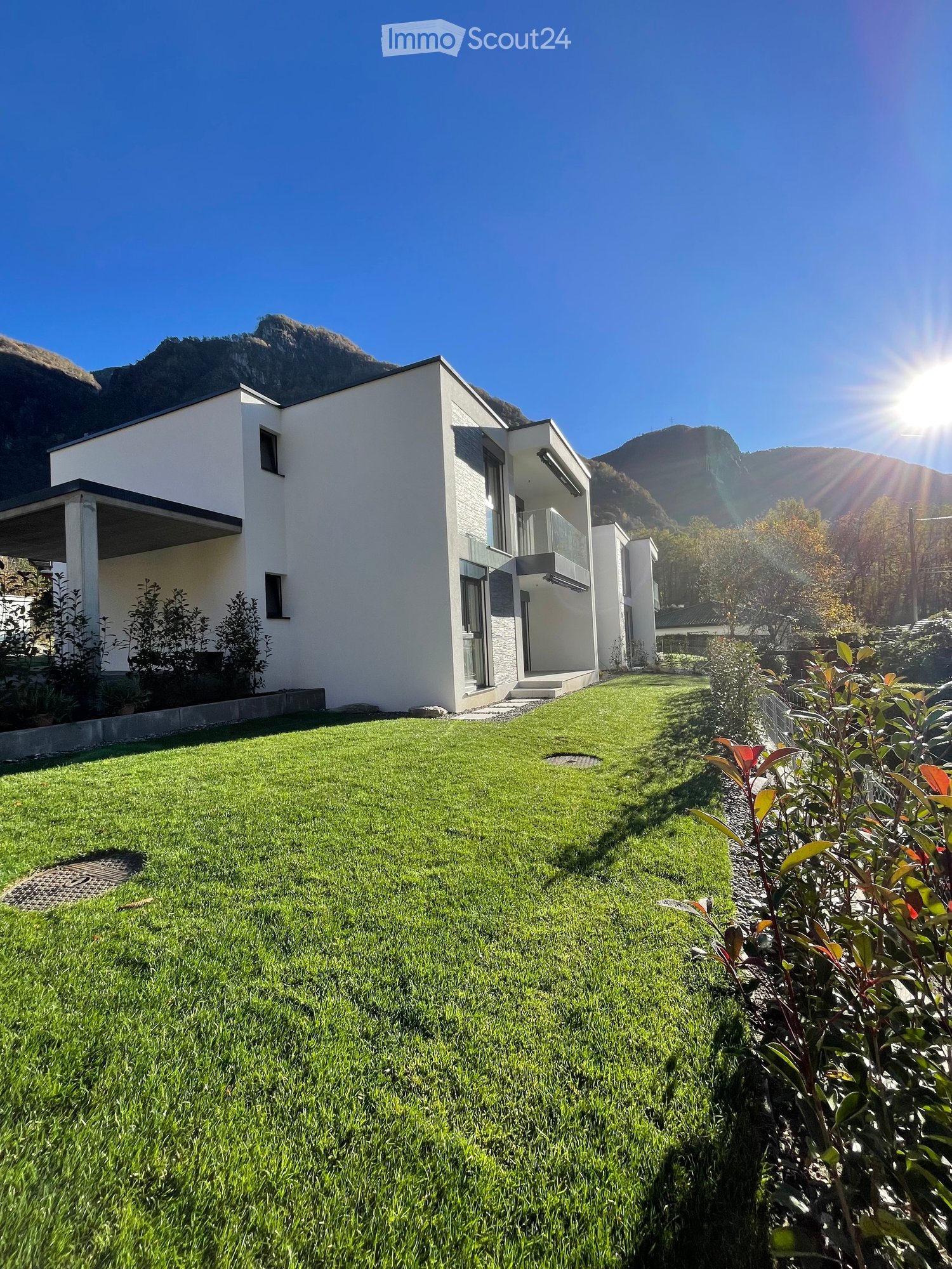 modern white house, large windows, balcony, sloping roof, garden, trees, mountains in background