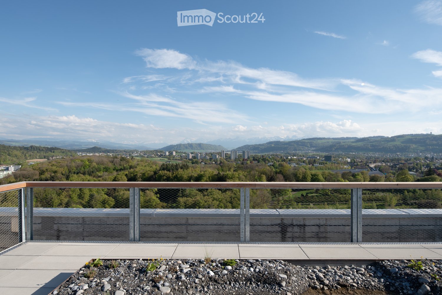 A balcony with a metal railing and a view of the city and mountains.