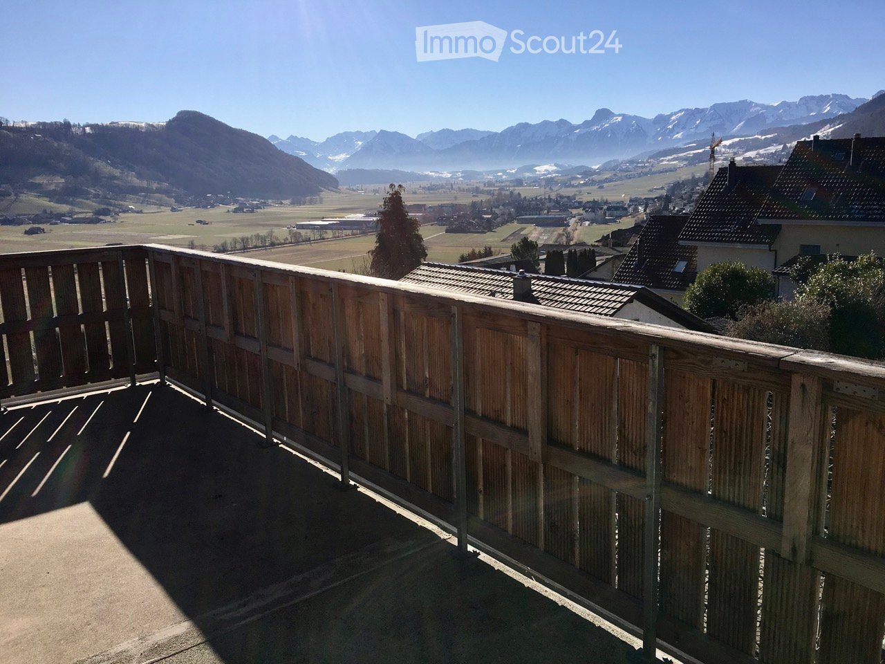 Balcony with wooden railing, overlooking valley and mountains