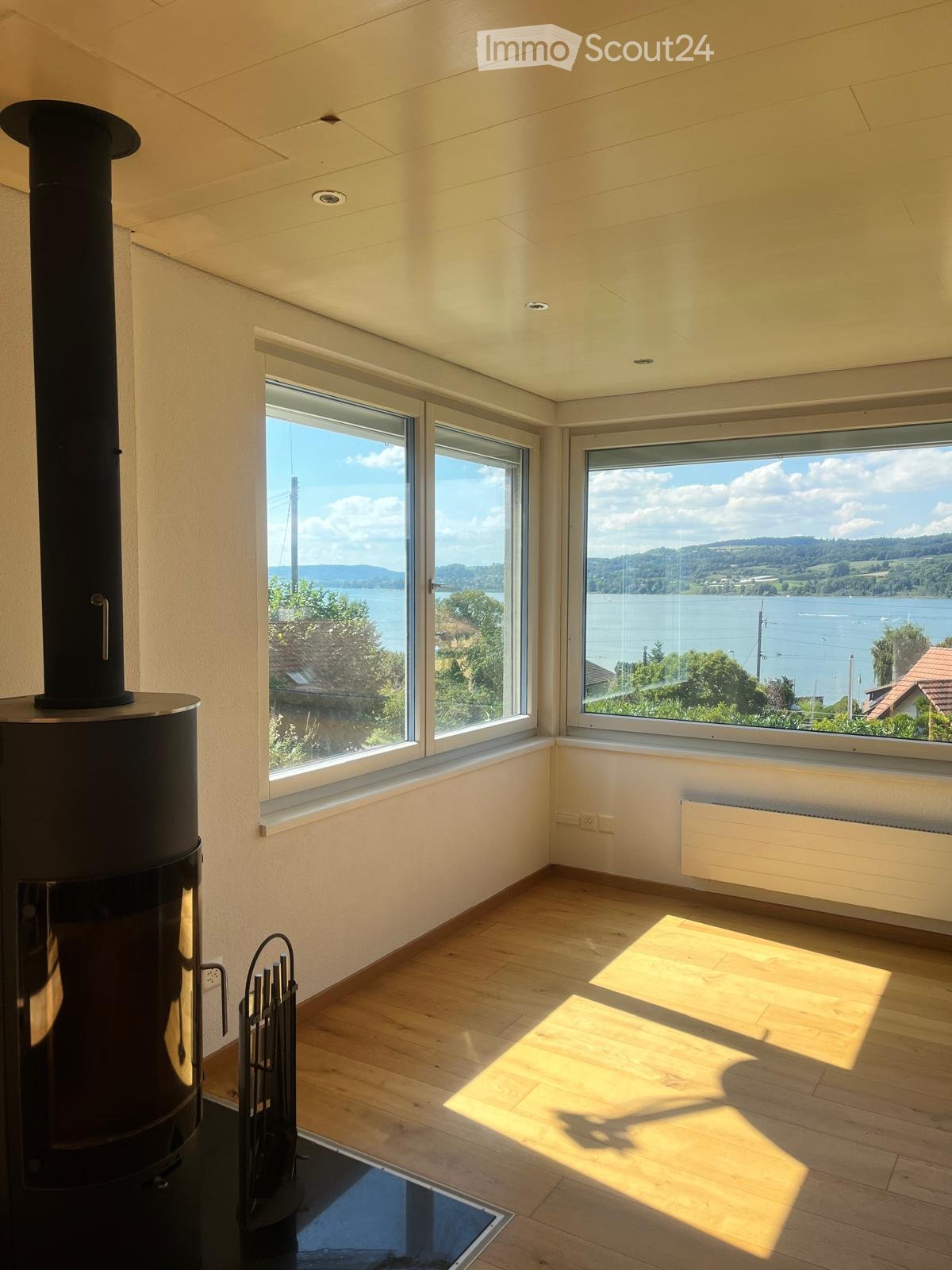 Wooden floor, fireplace, glass windows with view of lake