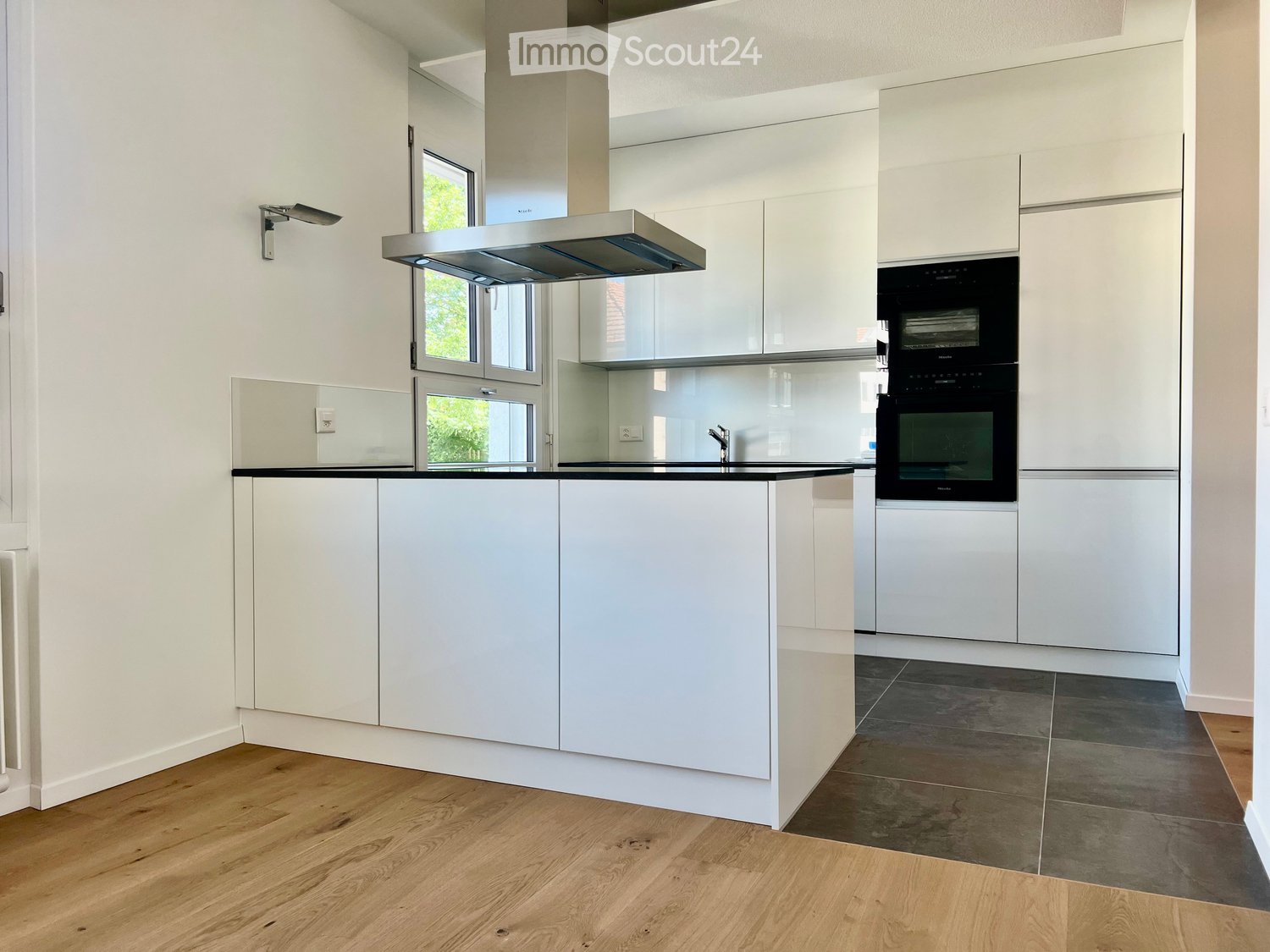 modern kitchen, white cabinets, wooden floors, black countertops, extractor hood, oven and dishwasher built-in