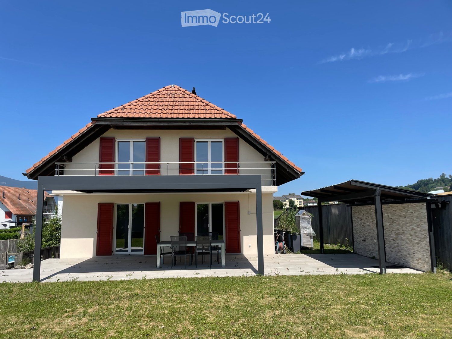 2 story house, red tiled roof, white walls, red shutters, covered balcony, outdoor dining table