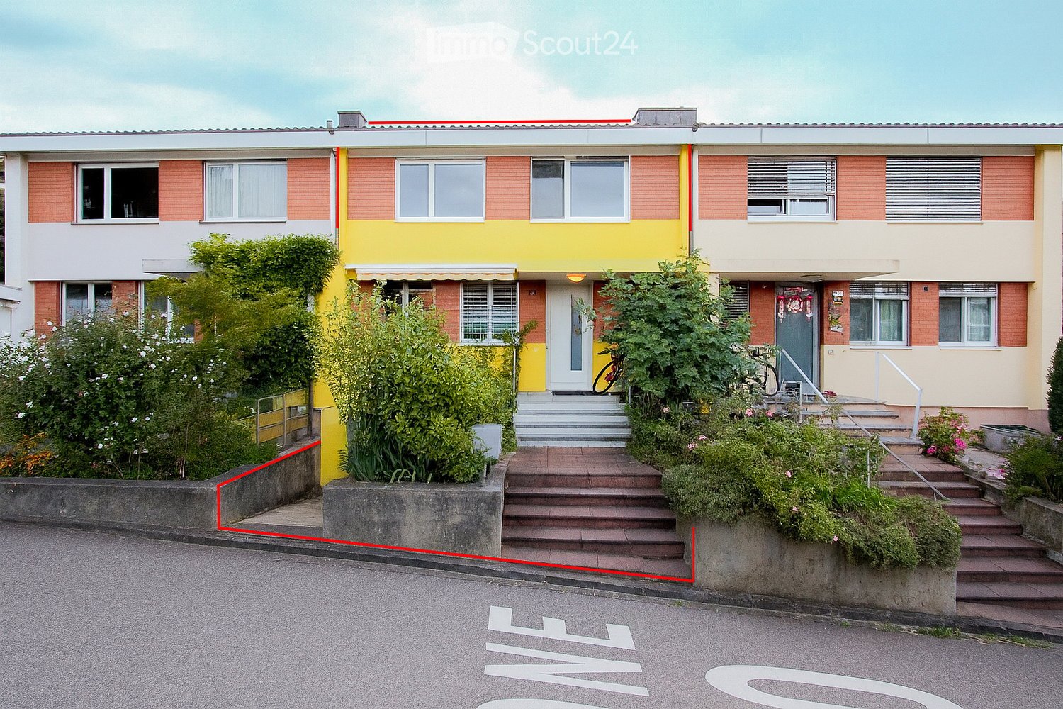 Row house, brick walls, yellow walls, glass windows, front door, staircases to entrance, plants in front