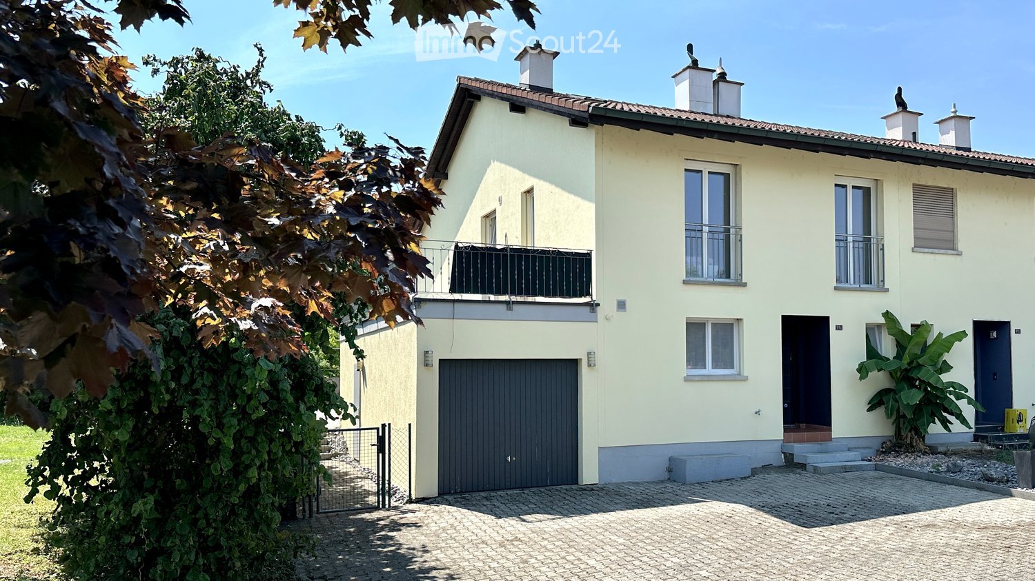 2 story house, yellow exterior, gray garage door, gray driveway, balcony on second floor