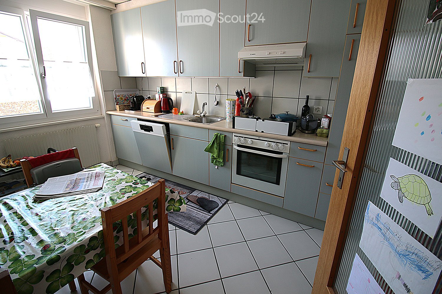 gray cabinets, white tiled floor, wooden dining table, oven, sink, dishwasher, window