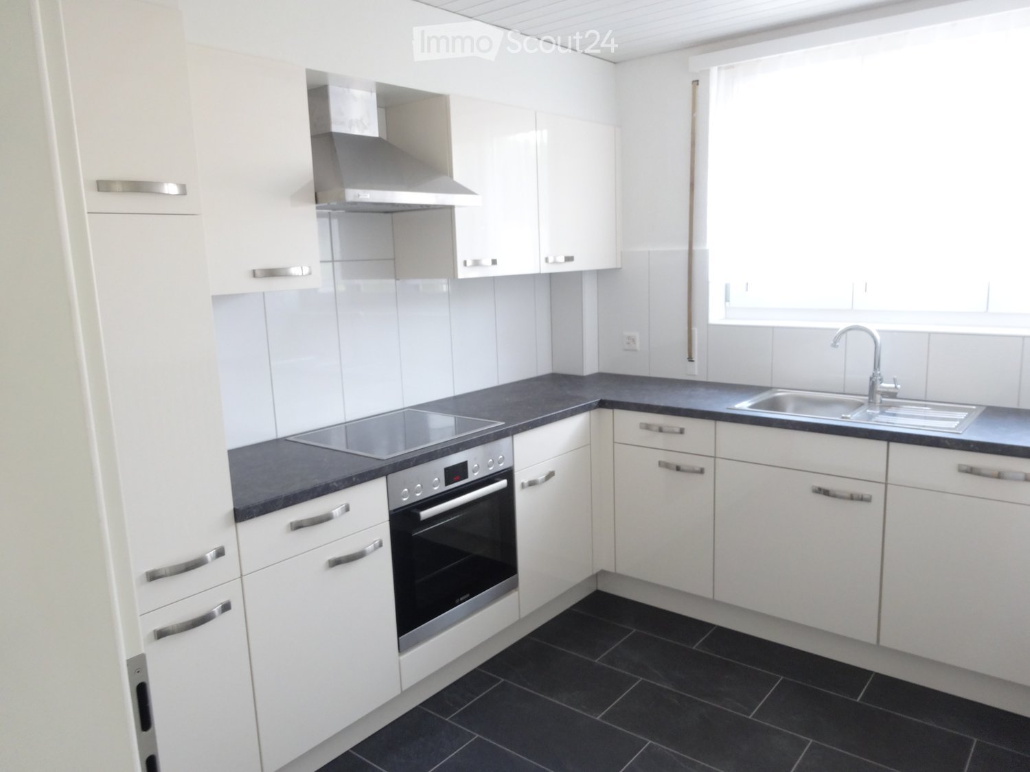 modern kitchen, white cabinets, black tiled floor, stainless steel appliances, under cabinet lighting, tiled backsplash