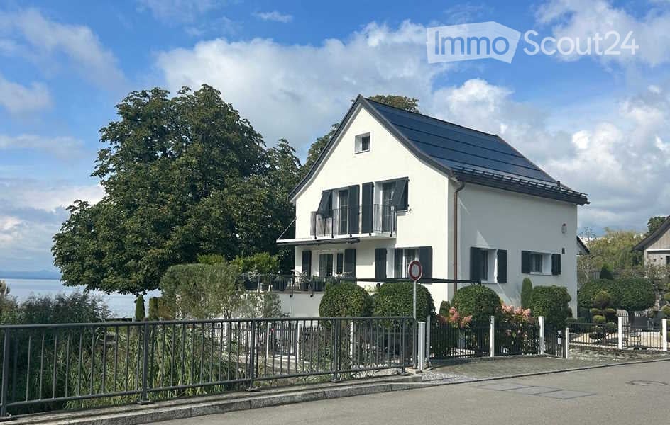 3 story house, white paint, solar panels on roof, lake view, fenced garden, gate