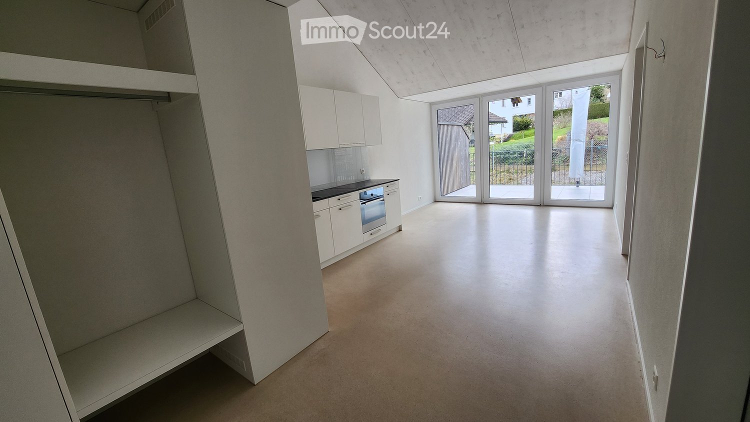 empty room with white wardrobe, white cabinets, black counter top, oven, sliding glass door with balcony view