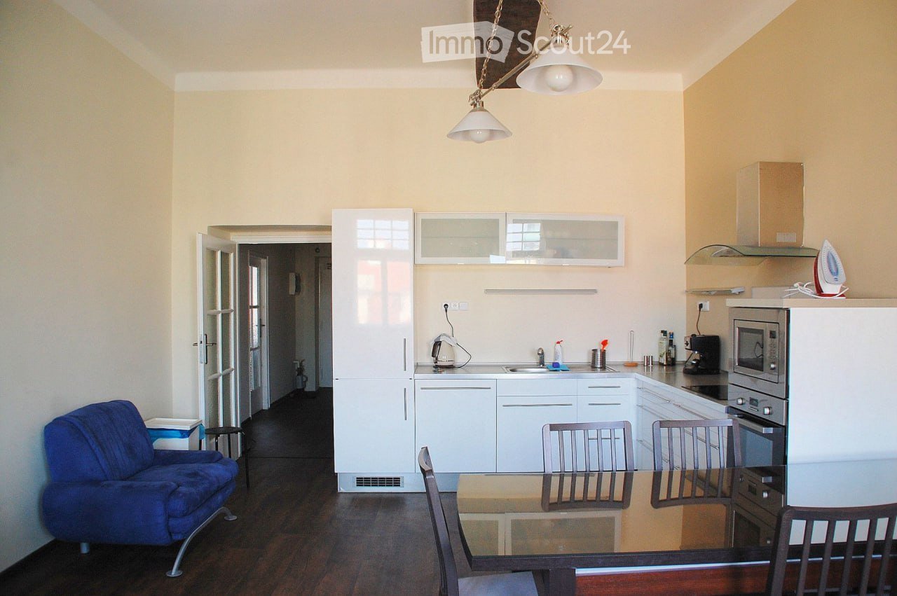 kitchen area with dining room, blue chair, white kitchen cabinets, light blue countertop, glass table, chairs, lamps, kitchen appliances, blue sofa