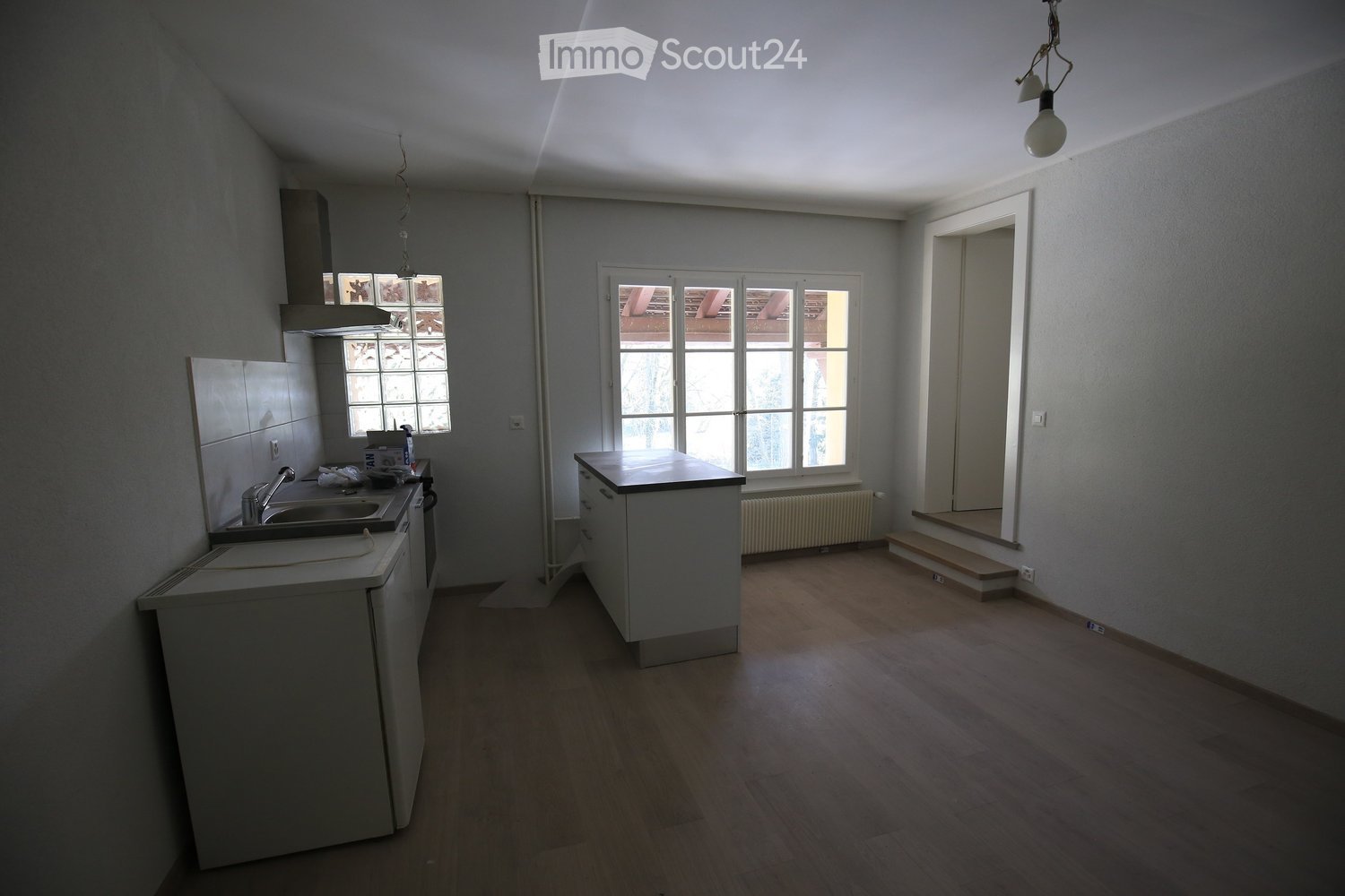 kitchen with a sink, gas stove, and white countertops, glass windows, white walls, wooden floor