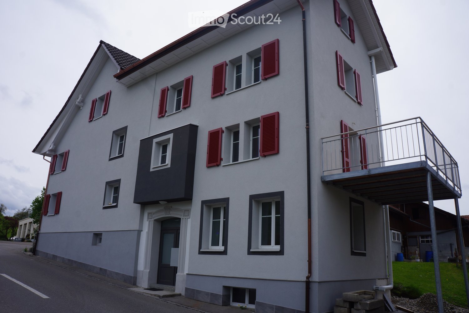 3-story white building, red shutters, balcony, black front entrance, ground-level