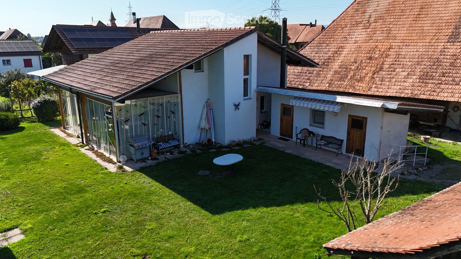 Single-family house, brown roof, white exterior, attached garage, spacious backyard, large patio, outdoor seating area, barbecue grill, solar panels