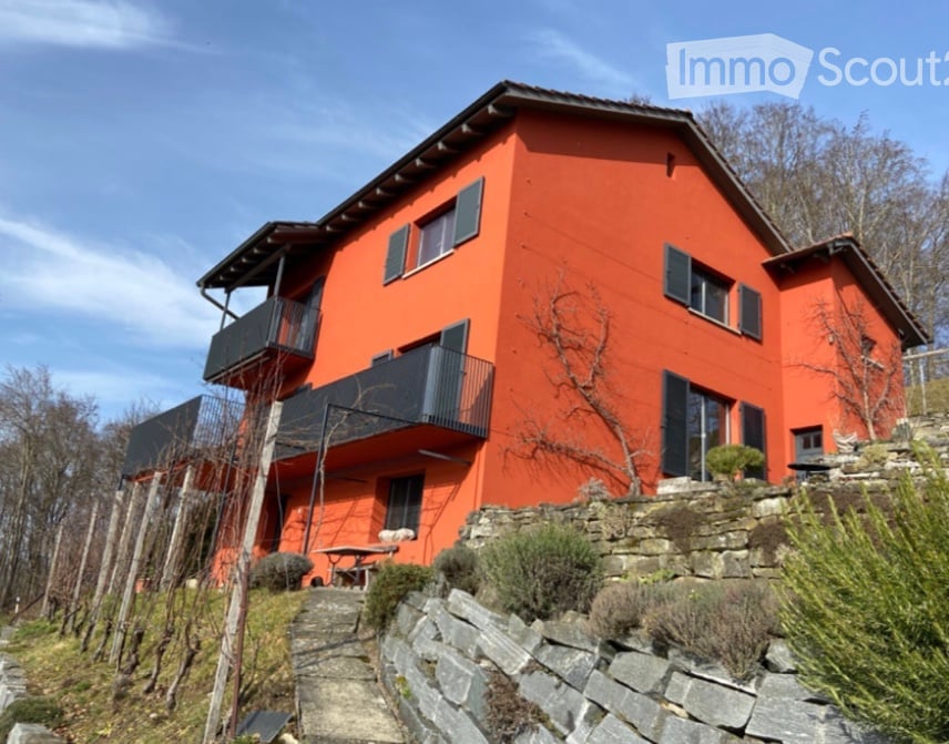 2 story house, orange exterior, black trim, stone wall, multiple balconies