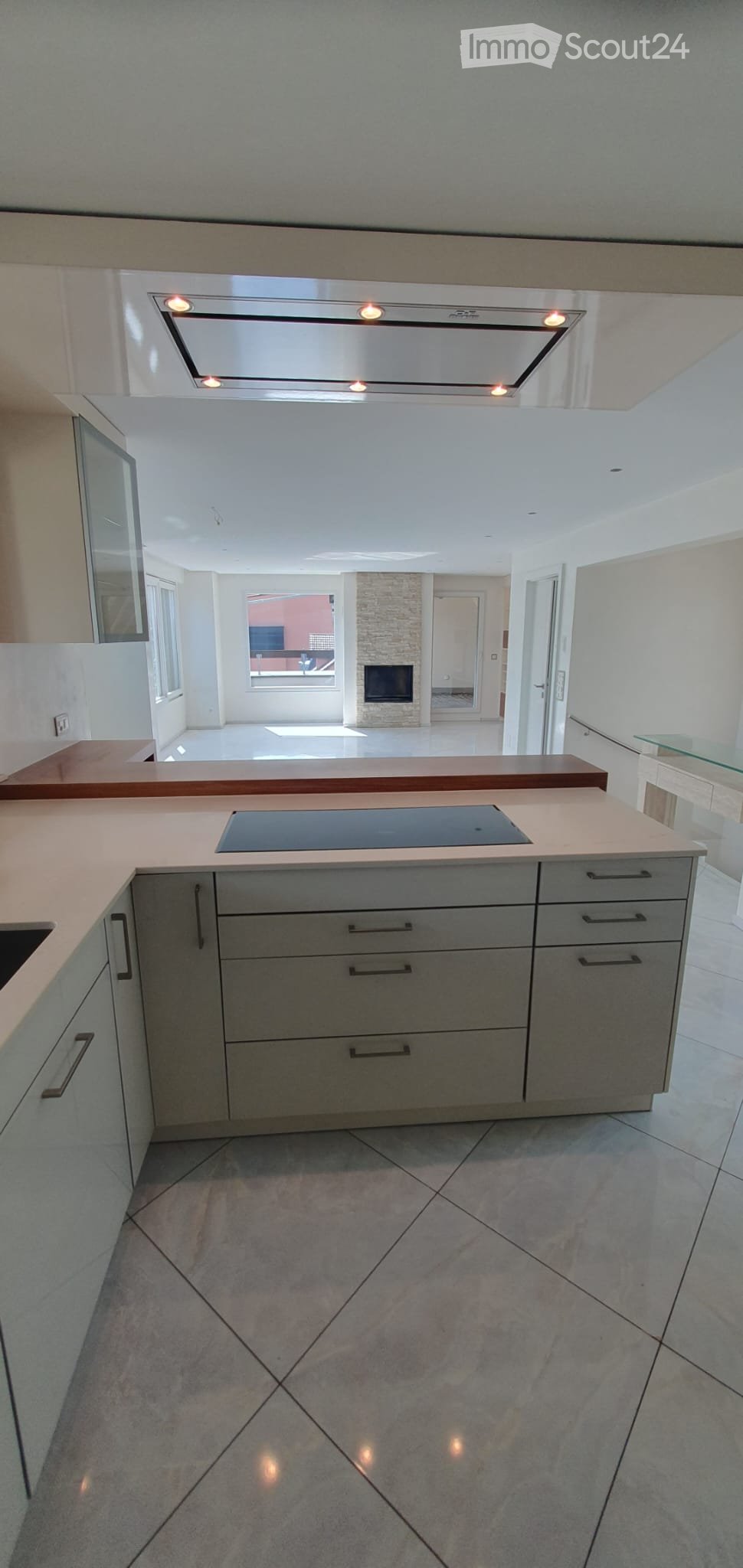 Open kitchen with white countertops, brown countertops, white cupboards, tiled floor, recessed lighting, a sink
