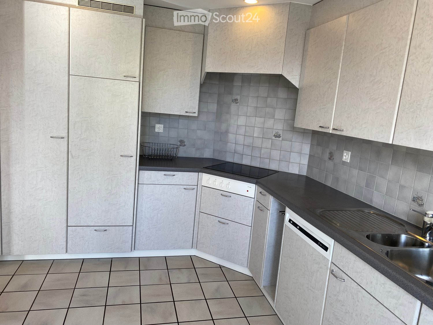 modern kitchen with white cabinets, gray tiled backsplash, black countertops, stainless steel sink with a faucet, a dishwasher, a white washing machine, and an electric stove