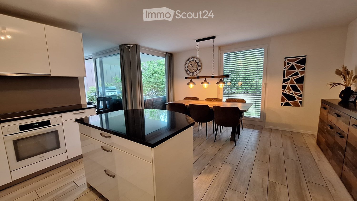 Open kitchen and dining area, sliding glass doors to balcony, dining table, white cabinets, oven, black counter top