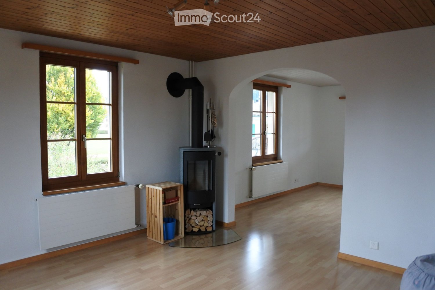 white walls, wooden floor, fireplace, 2 windows with white frames