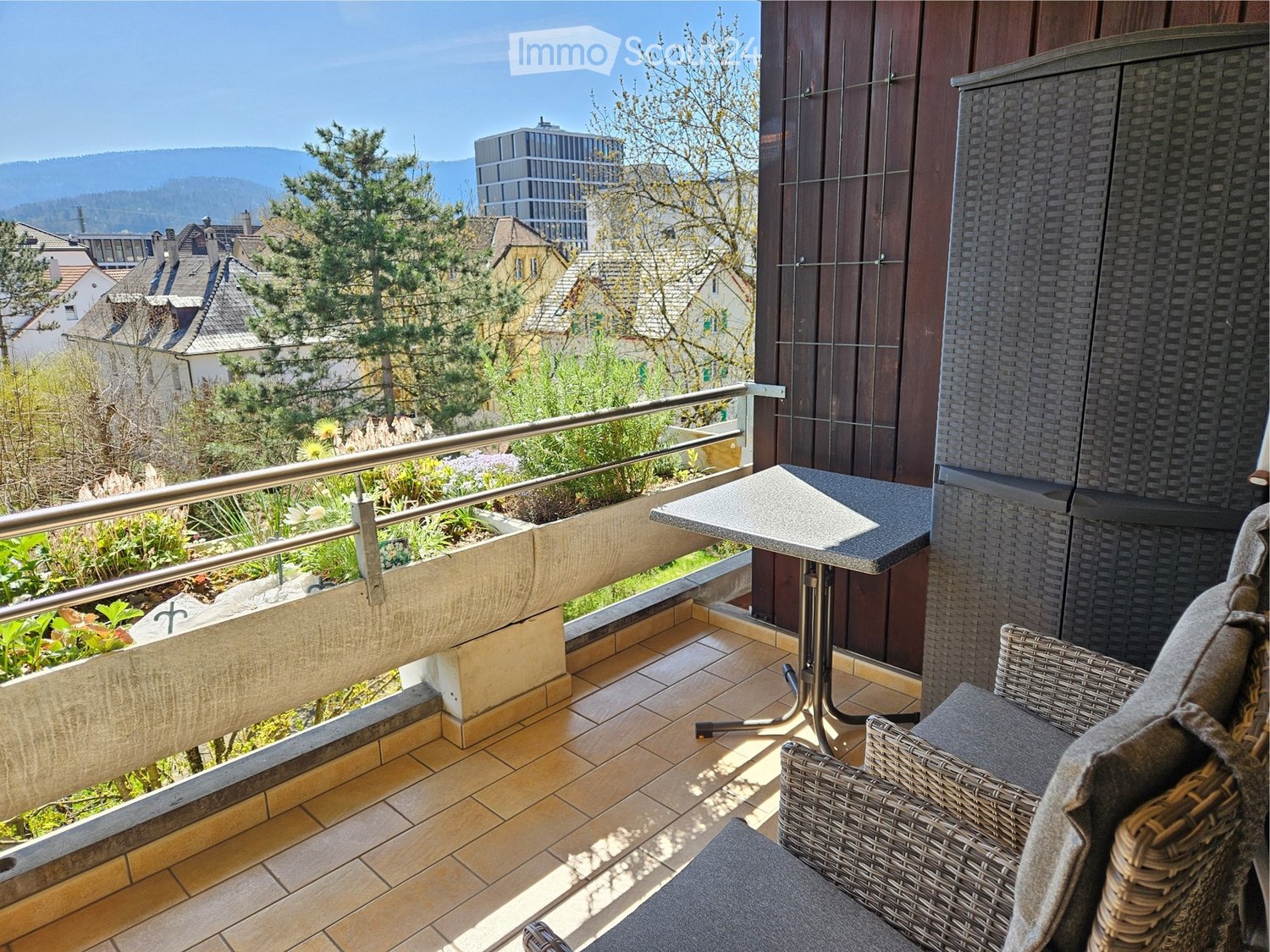 balcony with seating area, metal railing, table, chair, tile floor, view of town