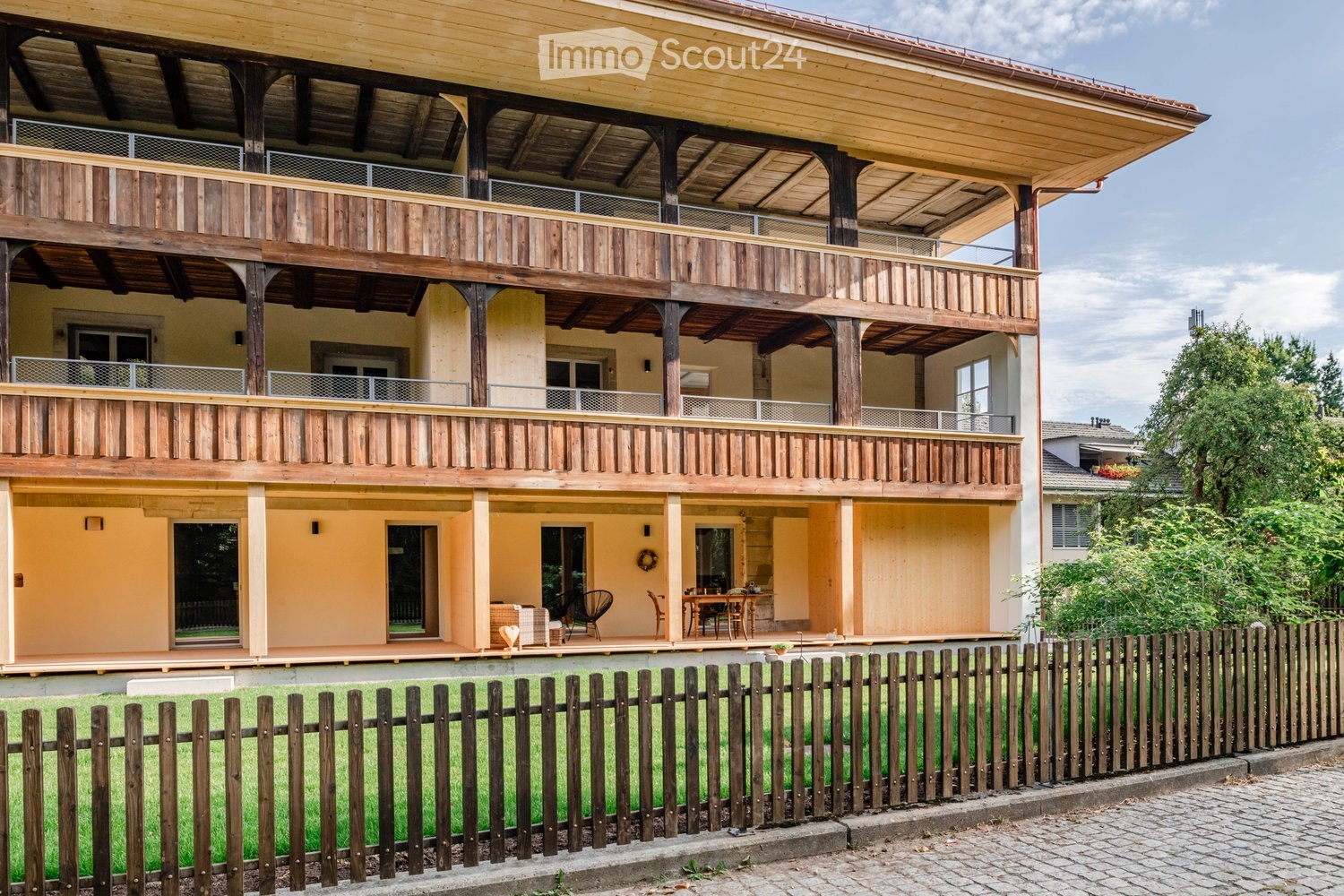 3-story wooden house, beige exterior, wooden balconies, wooden fence, garden