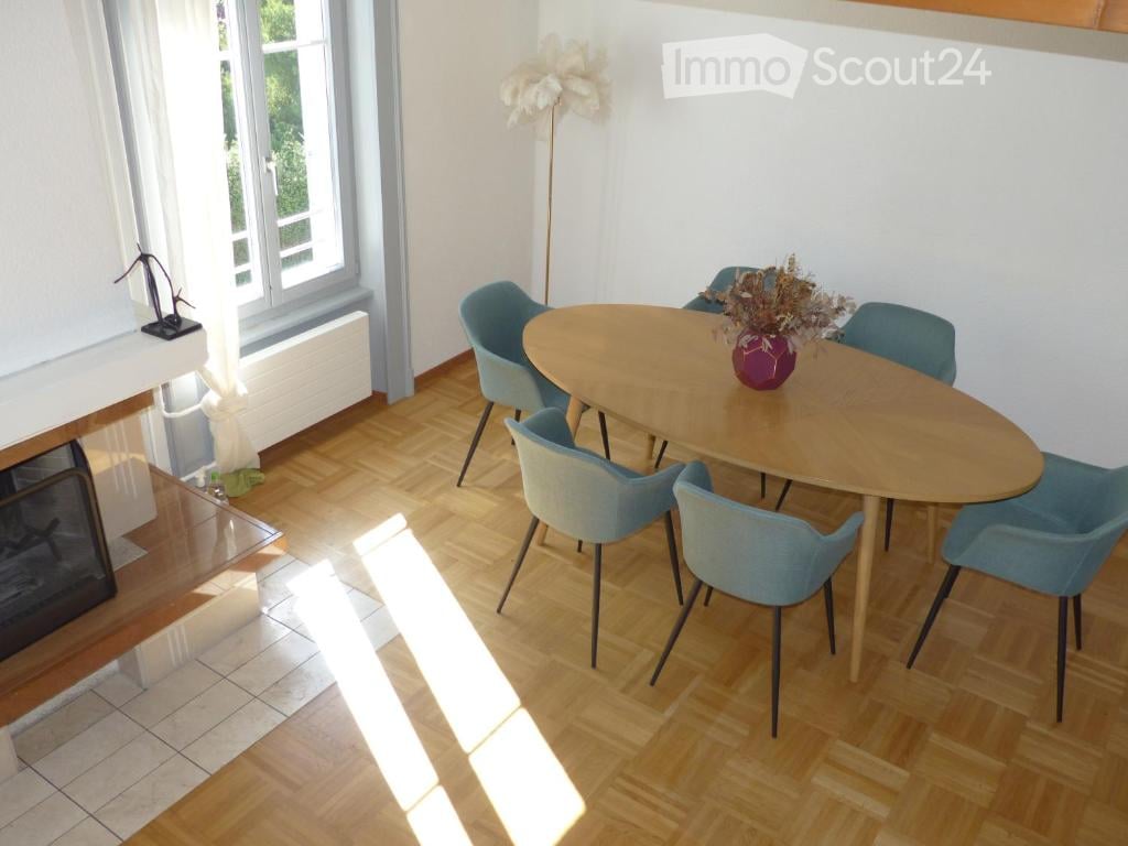 wooden floor, white walls, a fireplace, round table, blue chairs