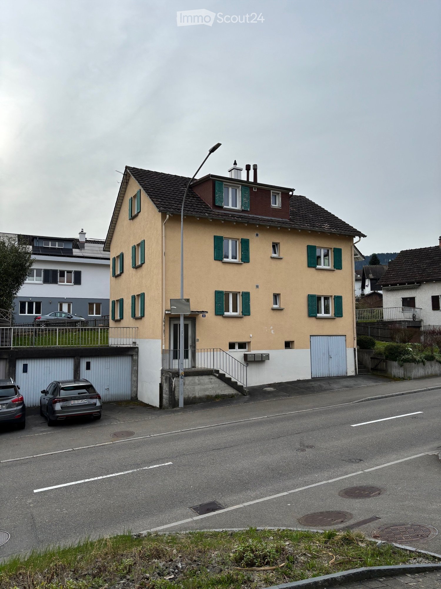3 story building, yellow and white exterior, green windows, garage