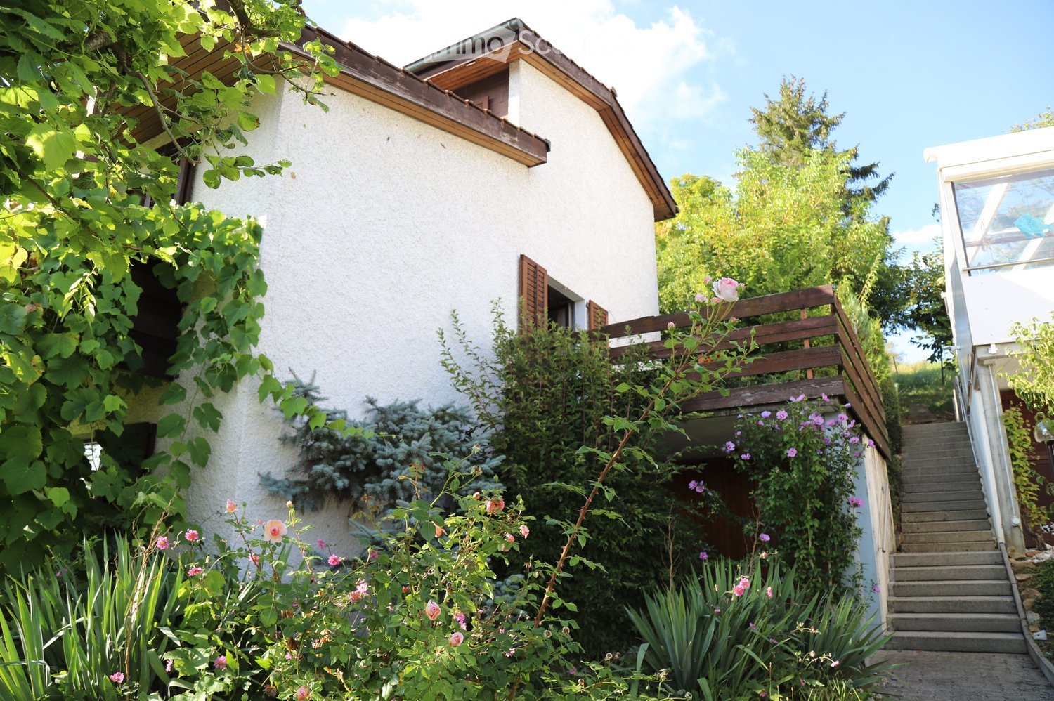 detached house, white exterior, wooden balcony, garden, shrubs and flowers