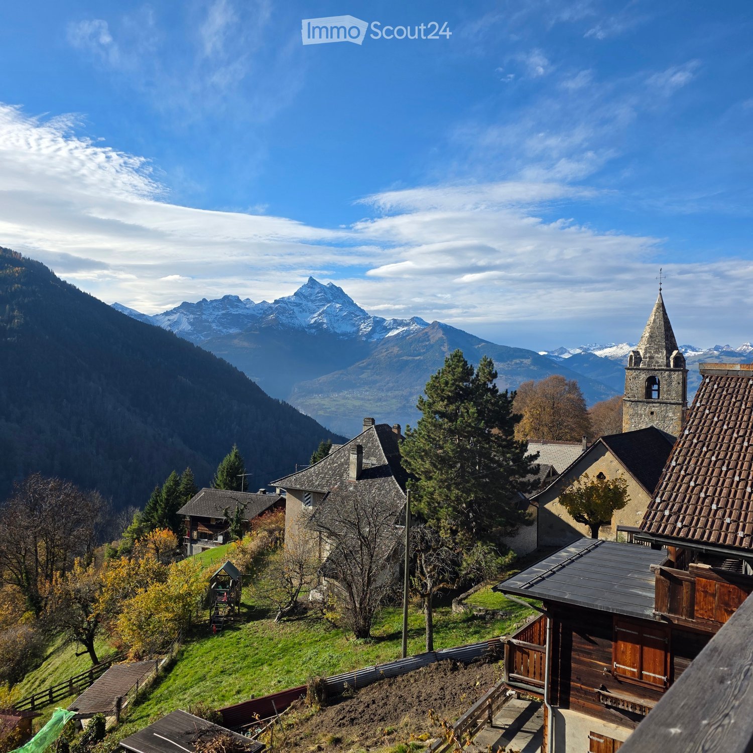 Village situated on a hillside, church with tower, mountain range in background