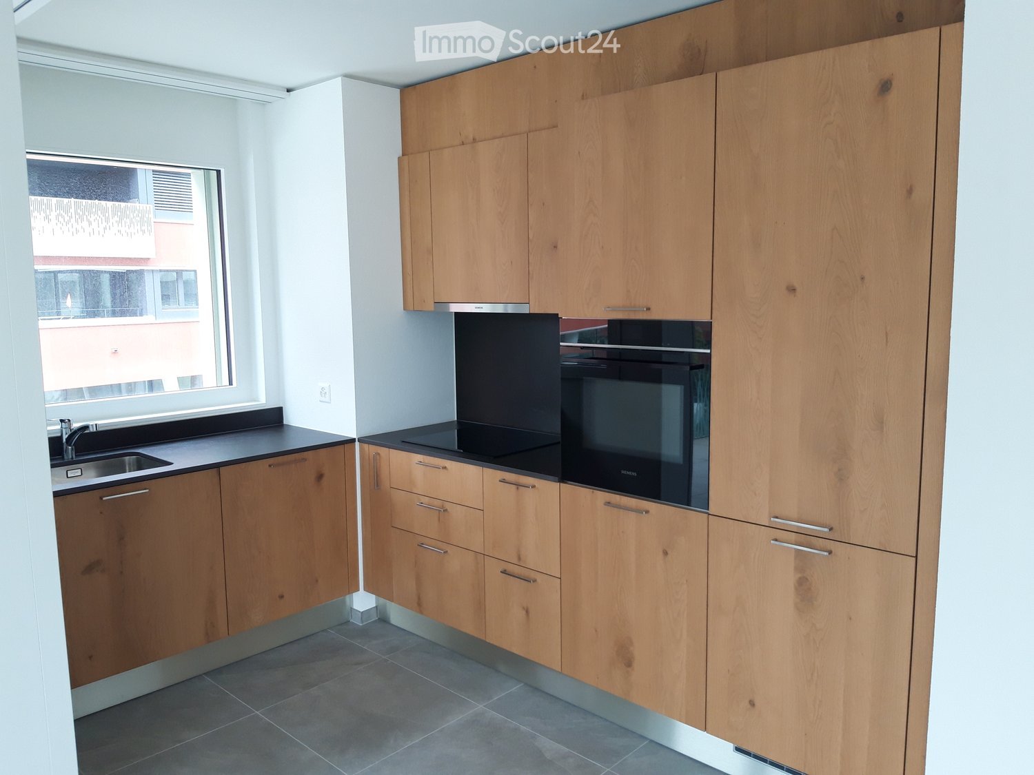 empty kitchen, wooden cabinets, black countertops, double oven, sink, window