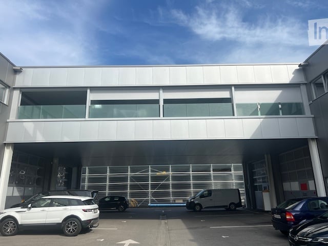 Modern commercial building, white facade, glass windows, parking area