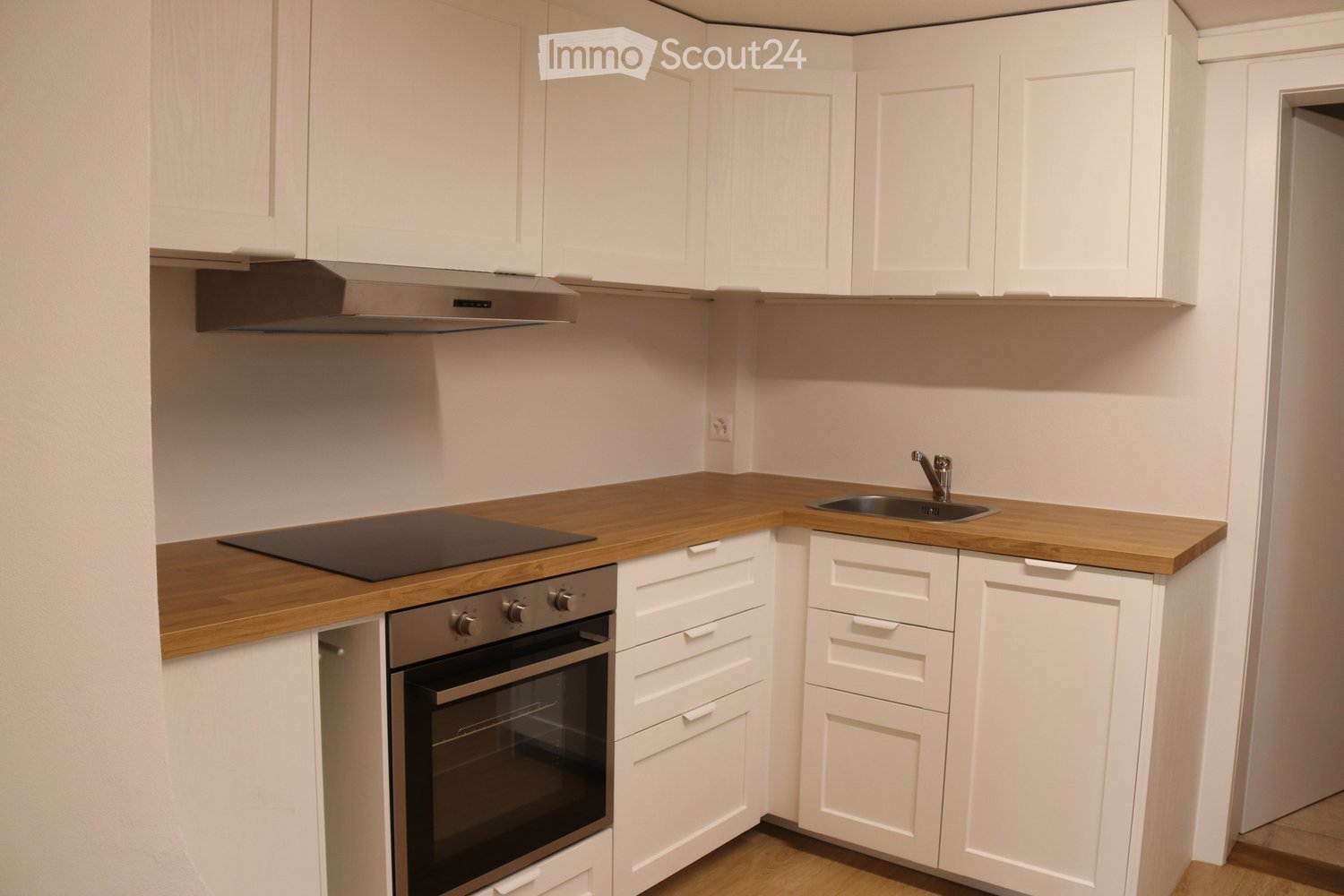 modern kitchen with white cabinets, wooden countertops, stainless steel oven, sink with faucet, and appliances