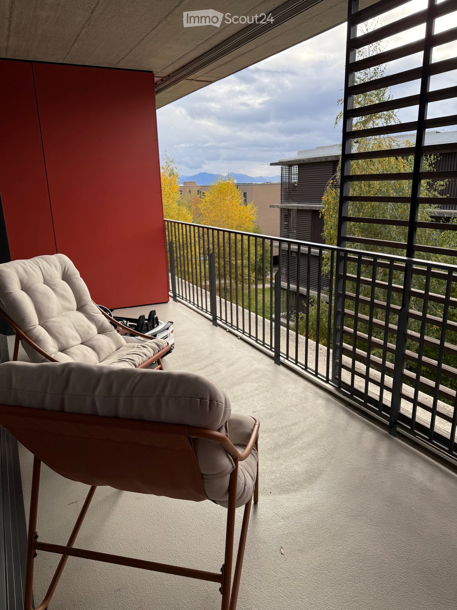 modern apartment balcony with a metal railing and two reclining chairs with cushioned seats