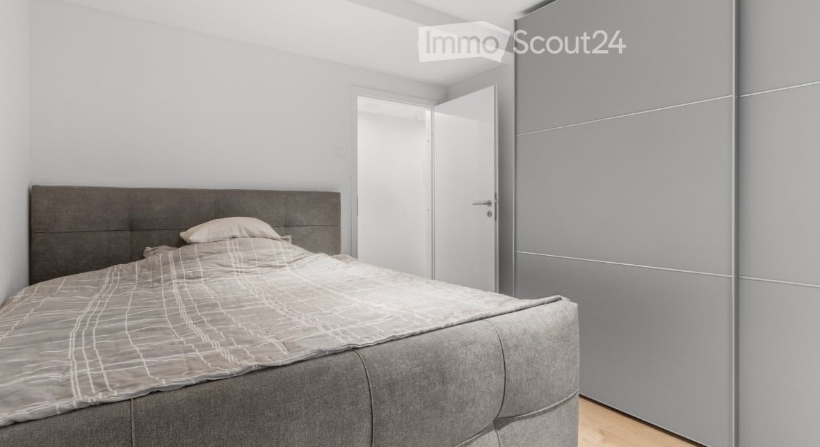 gray bed, gray headboard, gray walls, white door, light colored hardwood floors