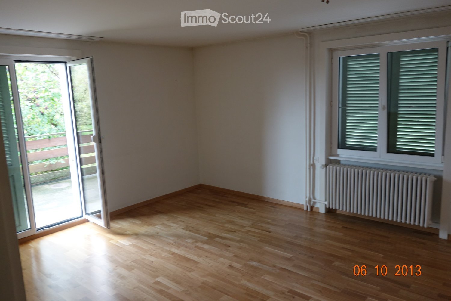 empty room, wooden floor, sliding door to balcony, window with shutters, white walls