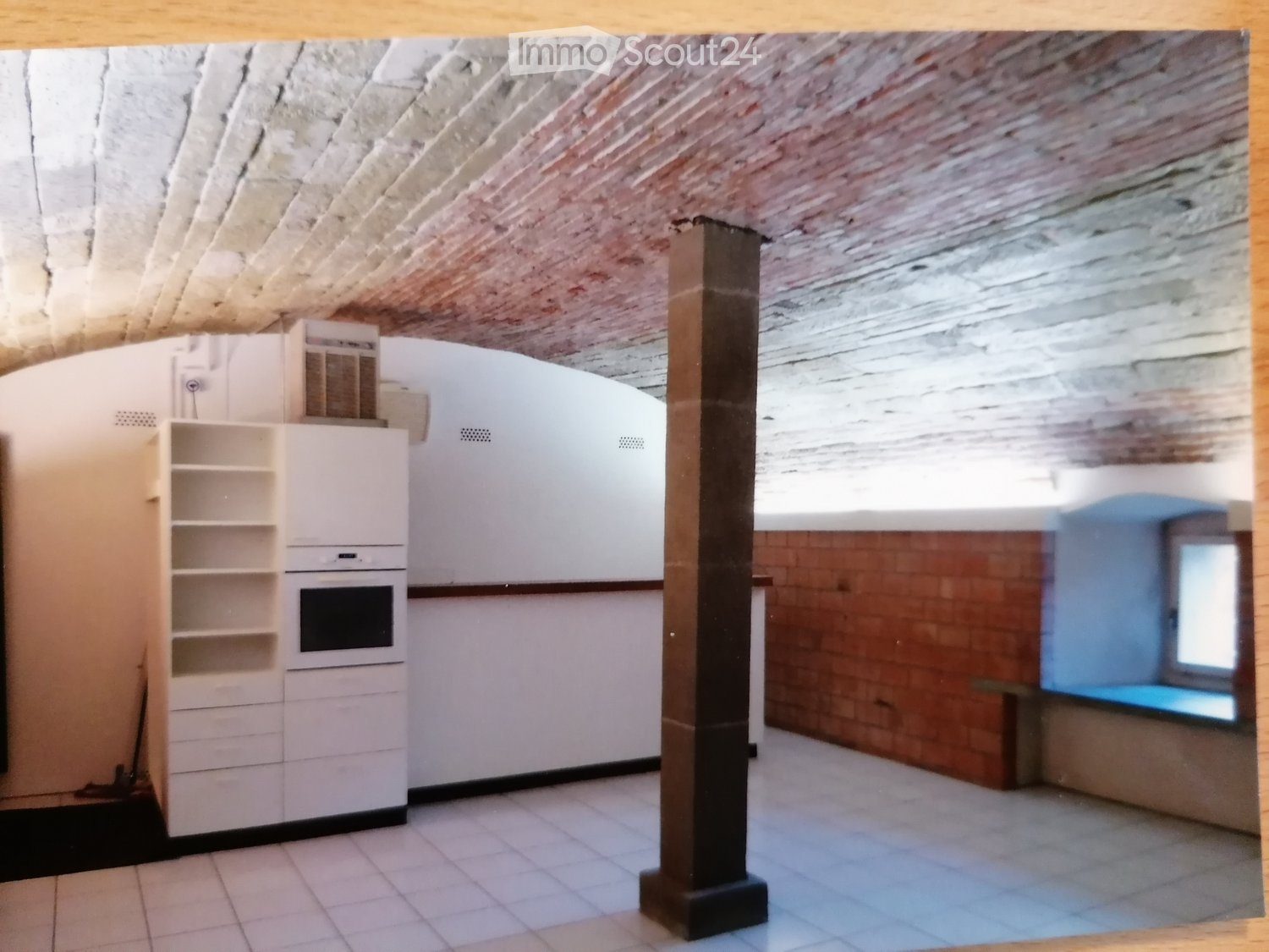 kitchen with white cabinets, white tiles, oven, air conditioner, brick column, brick wall, window