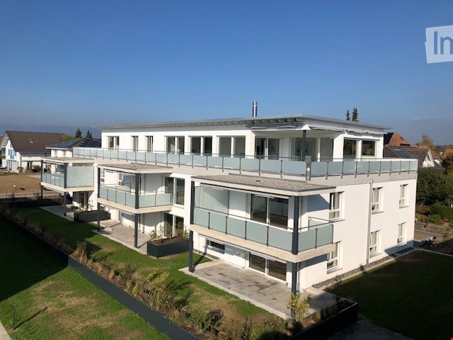 White building with 4 floors, multiple balconies, flat rooftop, landscaped surroundings