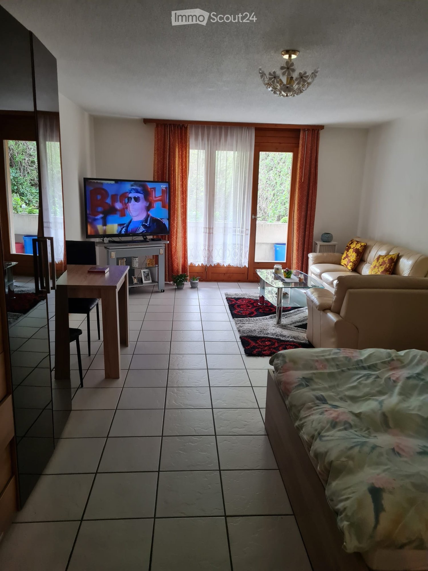 living room with couch, coffee table, television, white tile floor, wooden table and chairs, balcony, glass door, white curtains
