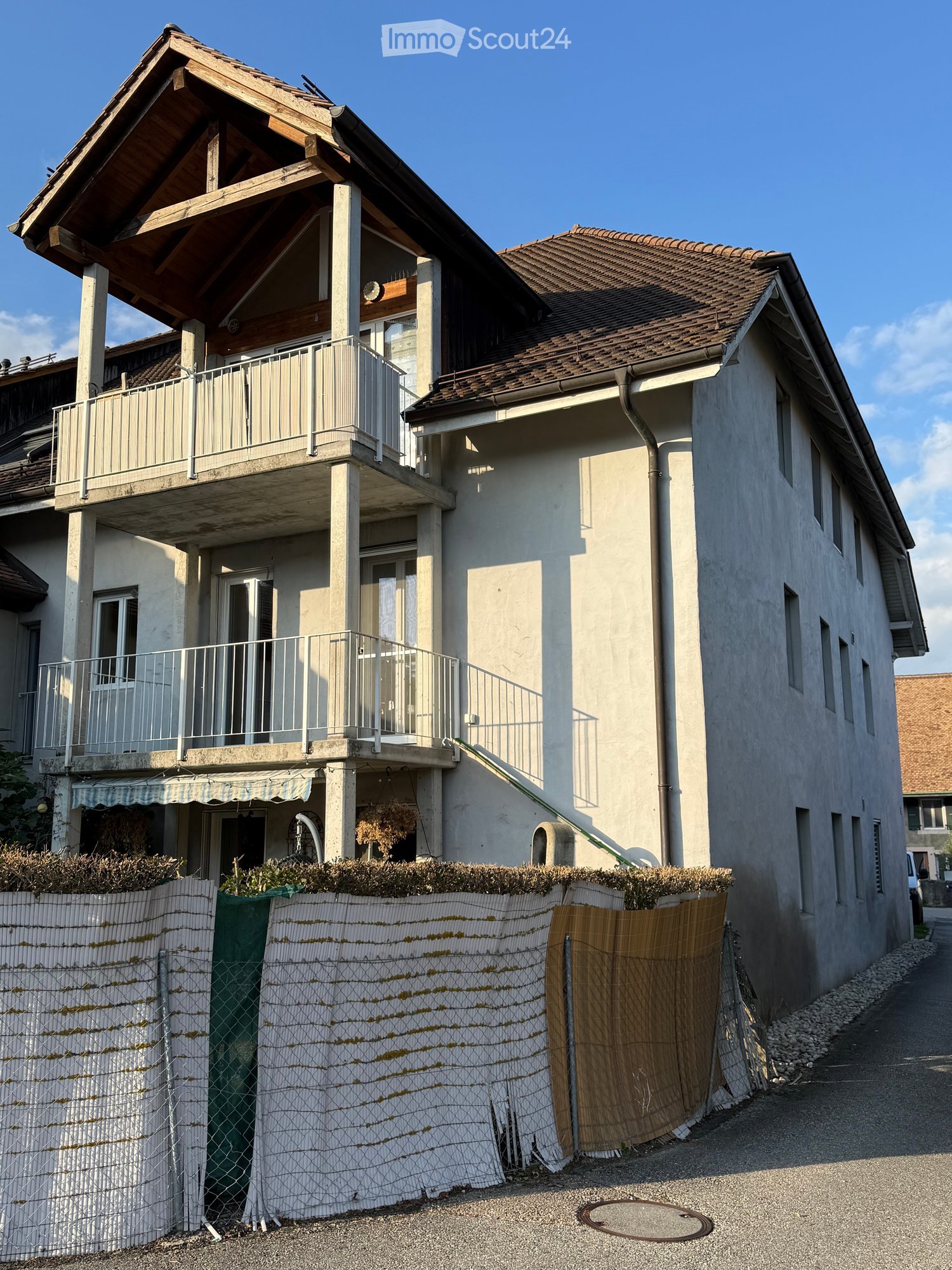 two story house, brown roof, beige walls, windows, balcony, stairs, fence