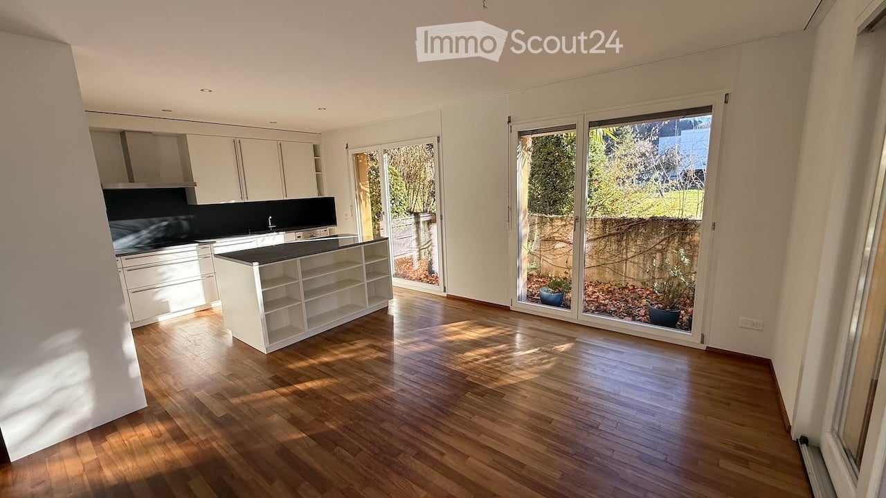 White cabinets, wooden floor, central island with sink, sliding glass doors, plants