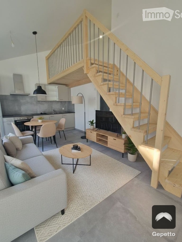 Living room with sofa, coffee table, wooden staircase, TV, potted plants, round table, chairs, kitchen with kitchen appliances, light fixture, white rug